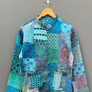 May include: A blue and green patchwork quilted jacket with a mandarin collar and button closure.