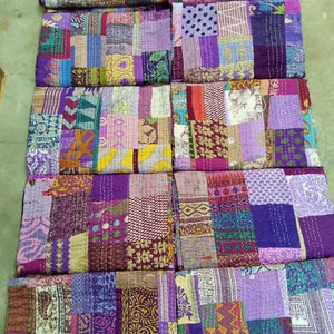 May include: A collection of eight patchwork quilts in various shades of purple, pink, green, and brown. The quilts are made of different fabrics and patterns, and they are all hand-stitched.