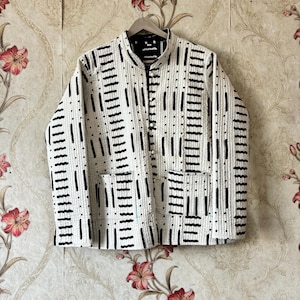 May include: A white quilted jacket with a black geometric pattern. The jacket has a mandarin collar and a button closure.
