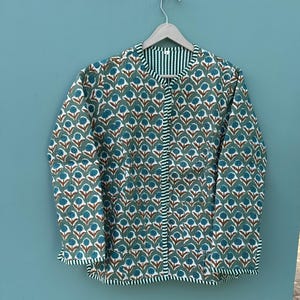 May include: A green and white quilted jacket with a floral print. The jacket has a button closure and long sleeves.