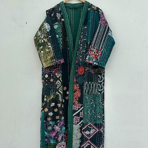 Könnte beinhalten: Langer Patchwork-Robe in Grüntönen mit floralen und geometrischen Mustern. Die Robe besteht aus verschiedenen Stoffstücken, die zusammengenäht sind, mit einem einfarbigen grünen Futter und Besatz. Sie hängt an einem Holzbügel.