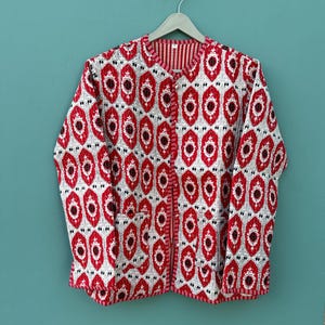 May include: A red and white patterned jacket with a button closure. The jacket has a diamond pattern with red circles in the center of each diamond.