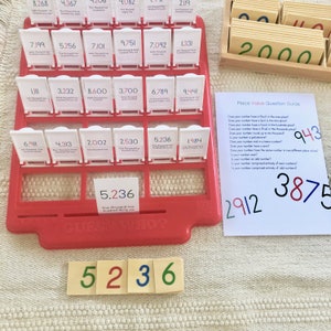 Op de afbeelding: Een rood plastic spelbord met witte kaarten met getallen van 1.000 tot 10.000. De kaarten zijn in een raster gerangschikt. Onder het spelbord bevinden zich vier kaarten met de getallen 5, 2, 3 en 6. Een wit vel papier met een plaatswaarde-vragenlijst en de getallen 943, 2912 en 3875 bevindt zich aan de rechterkant van de afbeelding.