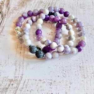 May include: Three layered bracelets with purple and white beads. The bracelets include lava rock beads and silver spacer beads.