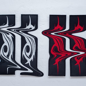 May include: Two sets of patches with a unique design. One set features a black background with white, flowing, tribal-inspired patterns. The other set has a black background with red, flowing, tribal-inspired patterns. The patches have a rectangular top.