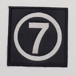 May include: Black fabric patch with a white circle and the number 7 in white.