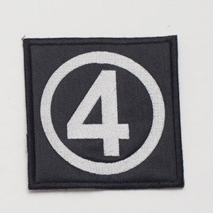 May include: A black fabric patch with a white circle containing the number "4" in white.