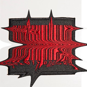 Puede incluir: Parche bordado rojo y negro con un diseño de código de barras distorsionado. Los números del código de barras son visibles: 86170221.