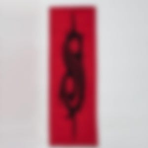 May include: A red rectangular object with a black silhouette design. The design appears to be a stylized figure or shape. The background is plain white.