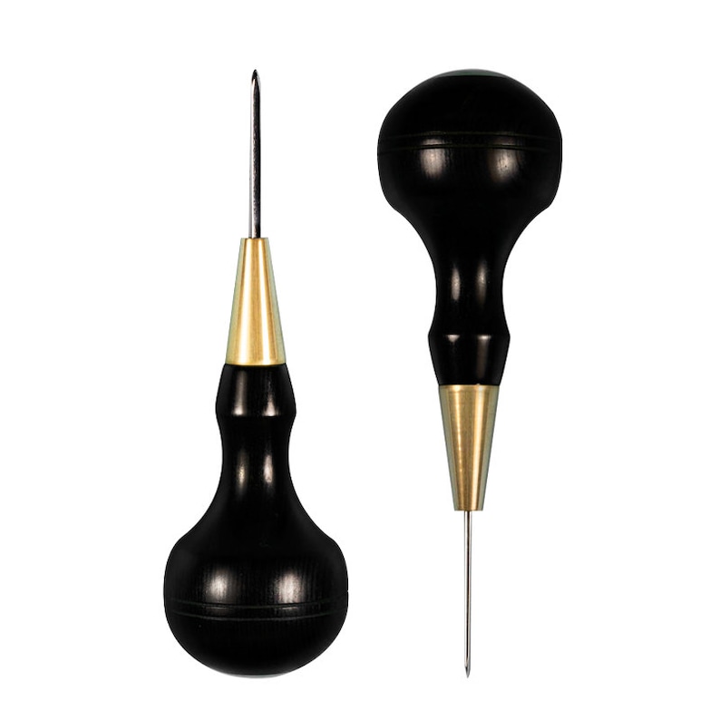 May include: Two leather crafting tools with black wooden handles and gold metal tips. The tools have a pointed tip and a rounded tip.