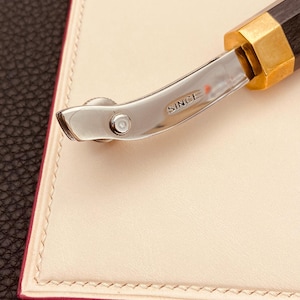 May include: A silver and black leather crafting tool with a rolling wheel and the word "SINCE" engraved on the handle.