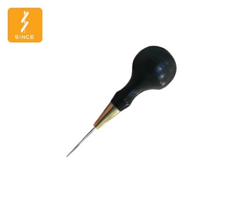 May include: A black leather awl with a brass tip and a black rubber handle.