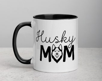 Può includere: Tazza in ceramica bianca con interno e manico neri. La tazza presenta le parole "Husky Mom" in corsivo nero e lettere maiuscole, con un'illustrazione di cane husky al centro.