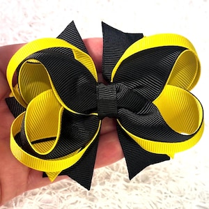 May include: A black and yellow hair bow with a double-loop design. The bow is made of grosgrain ribbon.