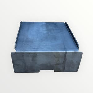 以下が含まれることがあります： すべての辺に盛り上がった縁のある正方形の金属製プラットフォーム。プラットフォームは濃いグレーの金属製で、滑らかでわずかにざらざらした表面をしています。