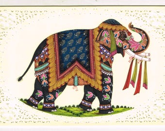 May include: A hand-painted illustration of an elephant adorned in colorful, intricate patterns. The elephant is depicted in a standing position with its trunk raised, showcasing a detailed design of floral motifs and geometric shapes. The artwork is set against a white background with a decorative border.