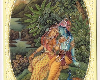 May include: A traditional Indian miniature painting depicting a couple in a lush green forest setting. The woman is wearing a yellow and red sari, while the man is wearing a blue and gold dhoti. They are surrounded by peacocks and other birds. The painting is framed in a white oval.