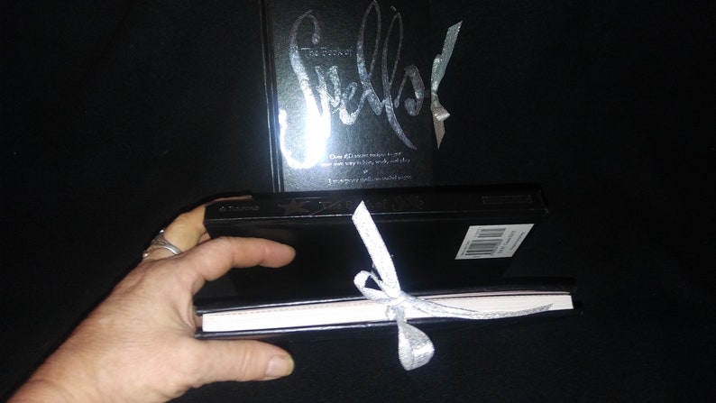 May include: Two black hardcover books with silver lettering. The larger book has the title "Sketch" and the smaller book is tied with a silver ribbon.