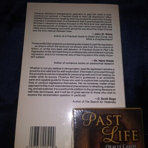 Puede incluir: Un libro titulado "A Practical Guide to Past Life Regression" de Florence McClain. La contraportada presenta citas de John W. White, Dr. Hans Holzer y D. Scott Rogo, todos autores de libros sobre el tema de las vidas pasadas y la reencarnaci&oacute;n. La portada del libro es blanca con texto negro.