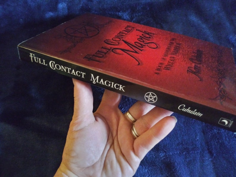 May include: A red book titled "Full Contact Magick" with a black pentagram on the cover. The book is a guide to Wiccan traditions.