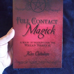 May include: A red book with the title "Full Contact Magick" and the subtitle "A Book of Shadows for the Wiccan Warrior". The author's name is Kerr Cuhulain.