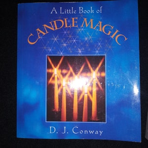 May include: A Little Book of Candle Magic by D. J. Conway. The book cover is a deep blue with the title in orange. The cover features an image of lit candles with bright flames.