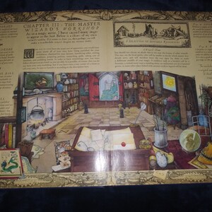 May include: Illustration of a wizard's workshop in an open book. The detailed interior includes bookshelves, a fireplace, and magical items. Text reads "Chapter III: The Master Wizard's Workshop".