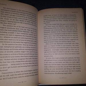 May include: Open book with the title "How to Be a Wicked Witch" and text about the basics of witchcraft. The book is open to pages 14 and 15. The text discusses the importance of a healthy dose of humor and taking action to improve your life.