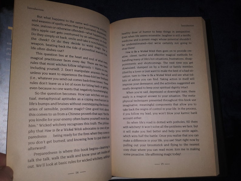 May include: Open book with the title "How to Be a Wicked Witch" and text about the basics of witchcraft. The book is open to pages 14 and 15. The text discusses the importance of a healthy dose of humor and taking action to improve your life.