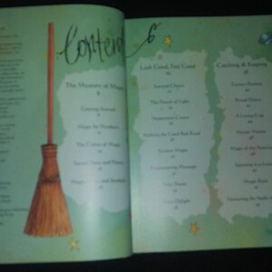 May include: An open book with a green cover and a table of contents. The book features a title called "The Mysteries of Magic" and a list of chapters including "Catching Rainbows" and "The Legend of the Red Road". A broom is illustrated on the left page.