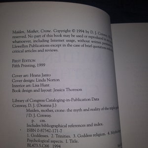 May include: A book titled "Maiden, Mother, Crone: The Myth and Reality of the Triple Goddess" by D.J. Conway. The book cover is white with black text. The book is a fifth printing from 1999.