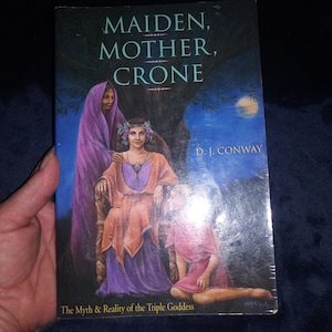 May include: Book cover with a painting of three women representing the Maiden, Mother, and Crone. The book title is "Maiden, Mother, Crone" by D.I. Conway. The subtitle is "The Myth & Reality of the Triple Goddess".