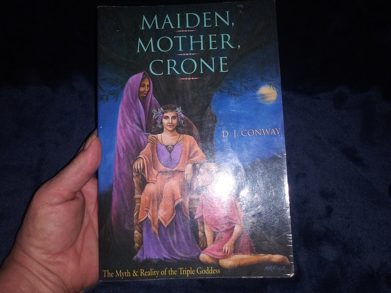 May include: Book cover with a painting of three women representing the Maiden, Mother, and Crone. The book title is "Maiden, Mother, Crone" by D.I. Conway. The subtitle is "The Myth & Reality of the Triple Goddess".
