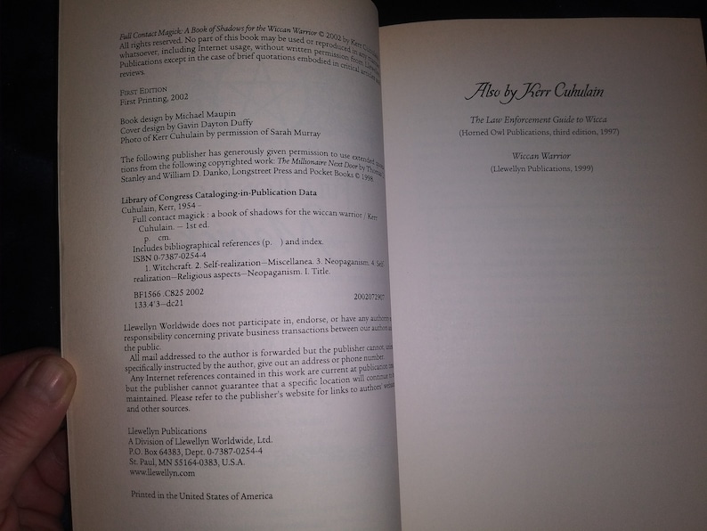 May include: A book titled "Full Contact Magick: A Book of Shadows for the Wiccan Warrior" by Kerr Cuhulain. The book cover is white with black text. The back cover lists other books by the author, including "The Law Enforcement Guide to Wicca" and "Wiccan Warrior".