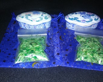 May include: Two small, oval-shaped porcelain boxes with blue and white floral designs. Each box is sitting on a blue velvet bag with silver stars and moons.  Each box is filled with green jade chips.
