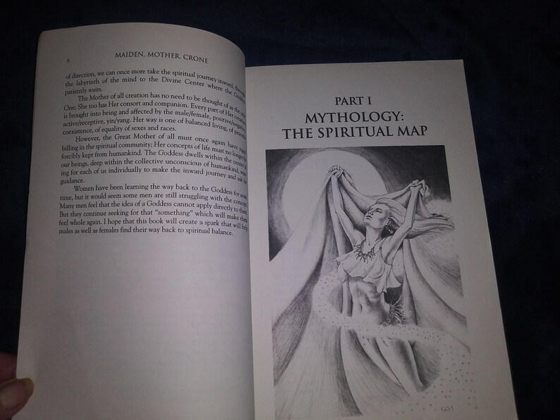 May include: A black and white illustration of a woman with long hair, wearing a flowing garment, standing with her arms raised above her head. The woman is surrounded by a swirling cloud of white dots. The text "PART I MYTHOLOGY: THE SPIRITUAL MAP" is printed in black at the top of the page.