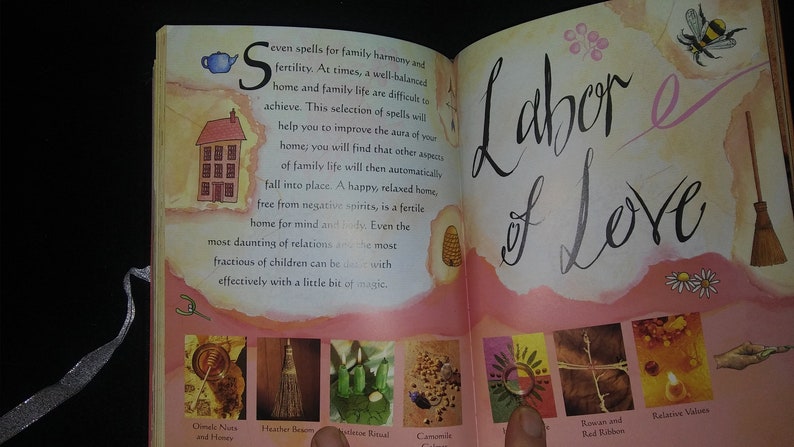 May include: Open book with a pink background and the title "Labor of Love". The book features illustrations of various ingredients and tools used in spells for family harmony and fertility. The text on the page describes the spells and their purpose.