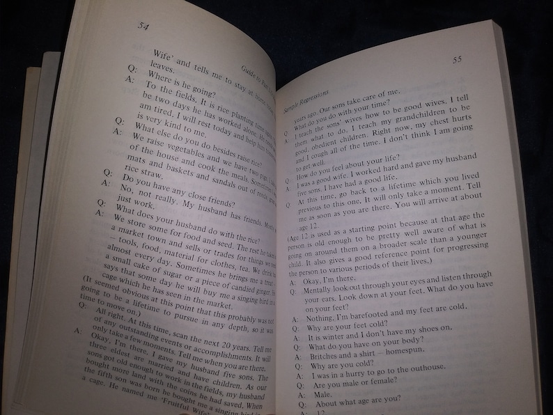 Puede incluir: Una fotograf&iacute;a en blanco y negro de un libro abierto en una p&aacute;gina con texto sobre la vida de una mujer y el trabajo de su marido. El texto incluye preguntas y respuestas sobre su rutina diaria y su vida familiar.