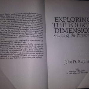 May include: A book cover with the title "Exploring the Fourth Dimension: Secrets of the Paranormal" by John D. Ralphs. The book cover is white with black text. The author's name is in a larger font size than the title.