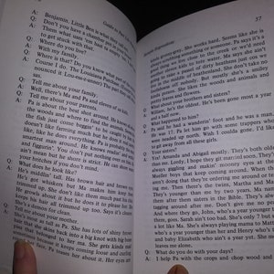 May include: A close-up of an open book with a brown cover. The book is titled "Guide to Poor Little Losers" and features a story about a family living in the Louisiana Purchase. The text is in black and white.