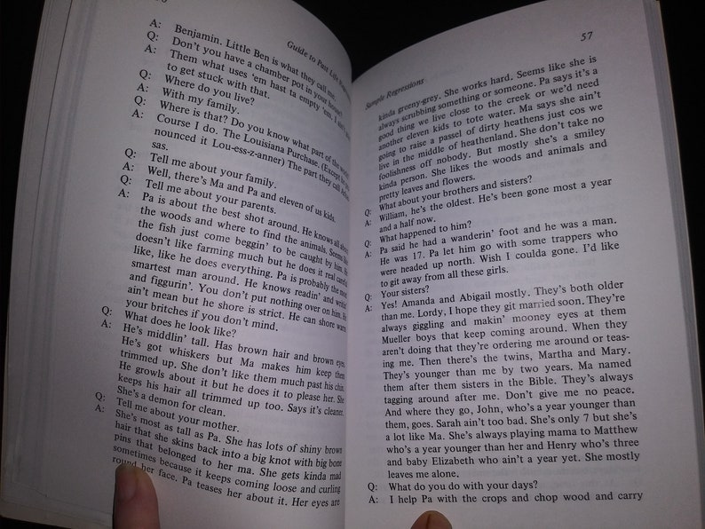 May include: A close-up of an open book with a brown cover. The book is titled "Guide to Poor Little Losers" and features a story about a family living in the Louisiana Purchase. The text is in black and white.