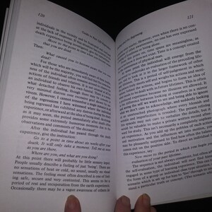 May include: A close-up of an open book with a white background. The book is open to a page with the title "Guide to Past Life Regression" and the text "What caused you to become aware that you were dead?" The page also includes text about the experience of death and the process of regression.