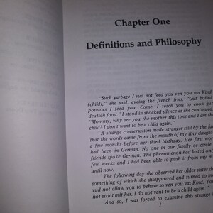 May include: A book open to a page titled "Chapter One: Definitions and Philosophy". The page contains text about a mother teaching her child to cook German food. The text discusses a strange conversation with the child who doesn't want to be a child again.