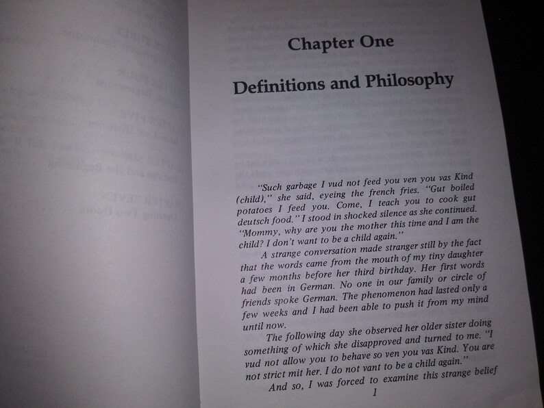 May include: A book open to a page titled "Chapter One: Definitions and Philosophy". The page contains text about a mother teaching her child to cook German food. The text discusses a strange conversation with the child who doesn't want to be a child again.