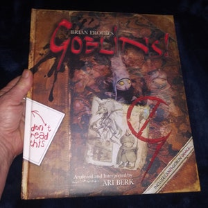 May include: A hardcover book titled "Brian Froud's Goblins!" with a detailed, fantasy-themed cover illustration in shades of brown, red, and purple. The book includes the text "Analyzed and Interpreted by Ari Berk" and a sticker that says "don't read this".