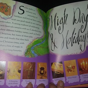 May include: An open book with a purple cover and a title that reads "High Days & Holidays". The book features illustrations of various holiday-themed items, including a suitcase, a whale, a traveler's amulet, a wish, a sandan vase, wheat husks, and candles.
