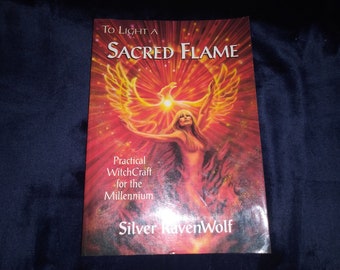 May include: Book cover with a phoenix rising from flames, a woman with long blonde hair standing in front of it, and the title "To Light a Sacred Flame: Practical WitchCraft for the Millennium" by Silver RavenWolf.