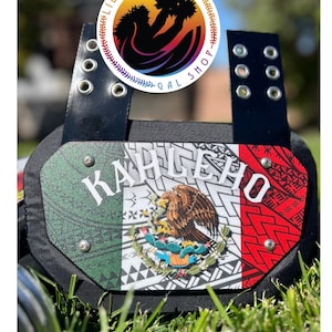 May include: A black football back plate featuring a central panel with the Mexican flag colors of green, white, and red, overlaid with a tribal pattern and the Mexican coat of arms. The text KAHLEHO is printed in white across the top center.