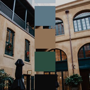 May include: An outdoor cafe scene with black umbrellas, tables, and chairs. The buildings are tan with dark green shutters and trim. A color palette of blue, brown, and green is overlaid on the image.