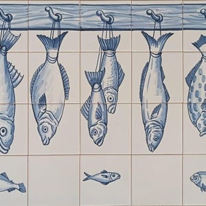 Puede incluir: Azulejos de cerámica azules y blancos que representan peces. Nueve peces cuelgan de ganchos en una viga de madera, con cinco peces más pequeños debajo. Diseño decorativo de azulejos.